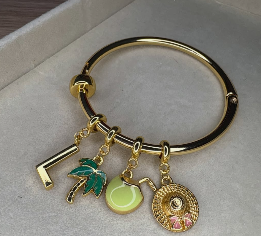 Pulseira dourada com pingentes de letra L, coqueiro, bola e chapéu